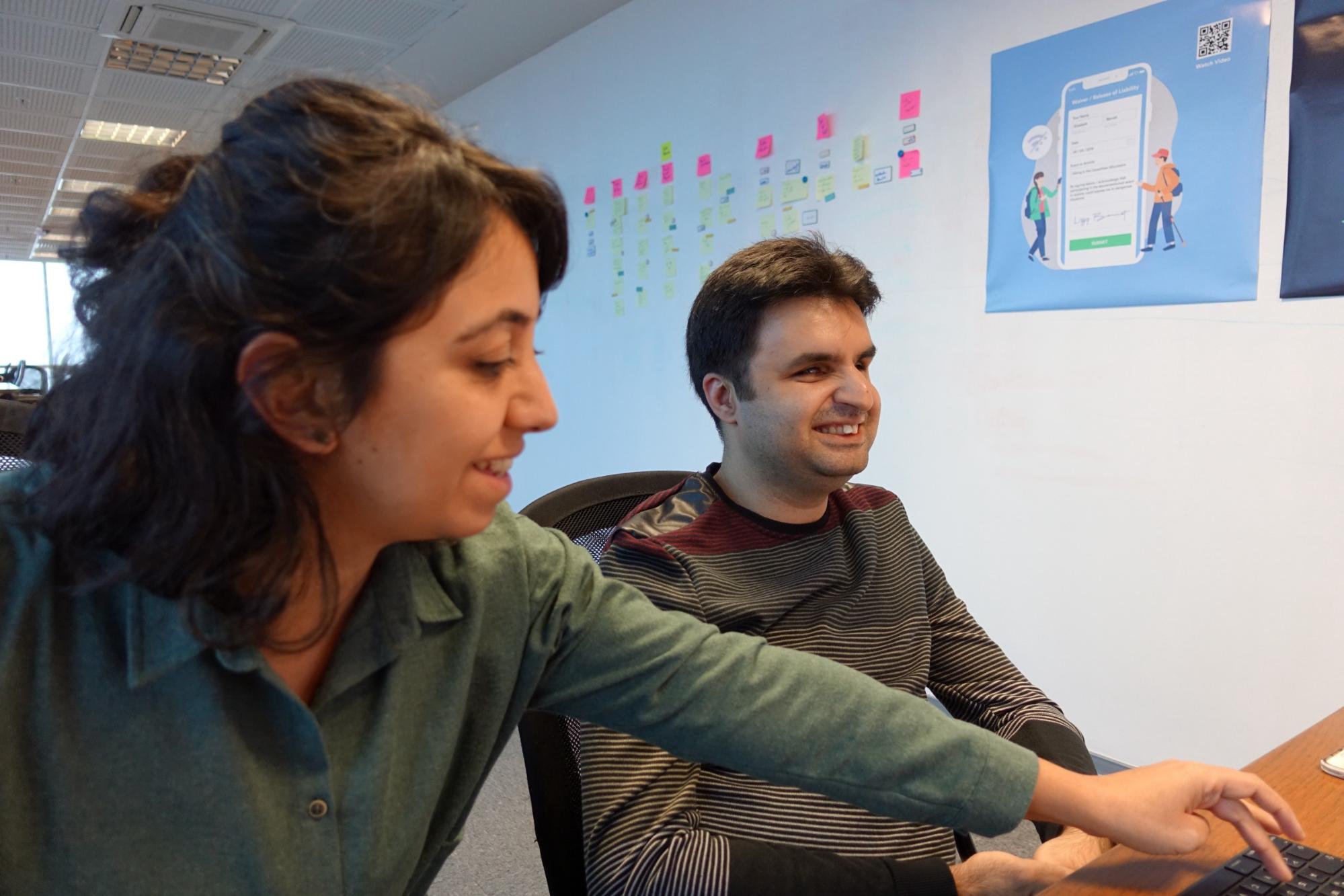 A photo of user researcher Gokce and Cagri having a usability test next to a white wall with post-its and posters on it