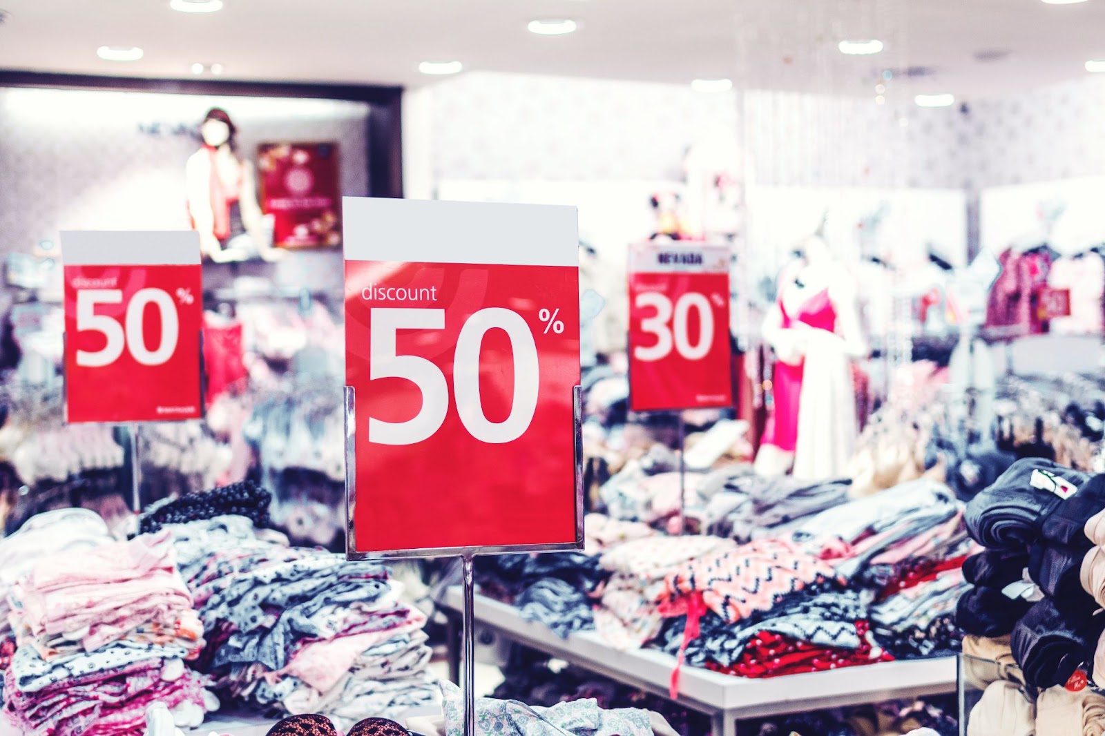 A blurry clothing store background with clear red '50% discount' signs in the foreground