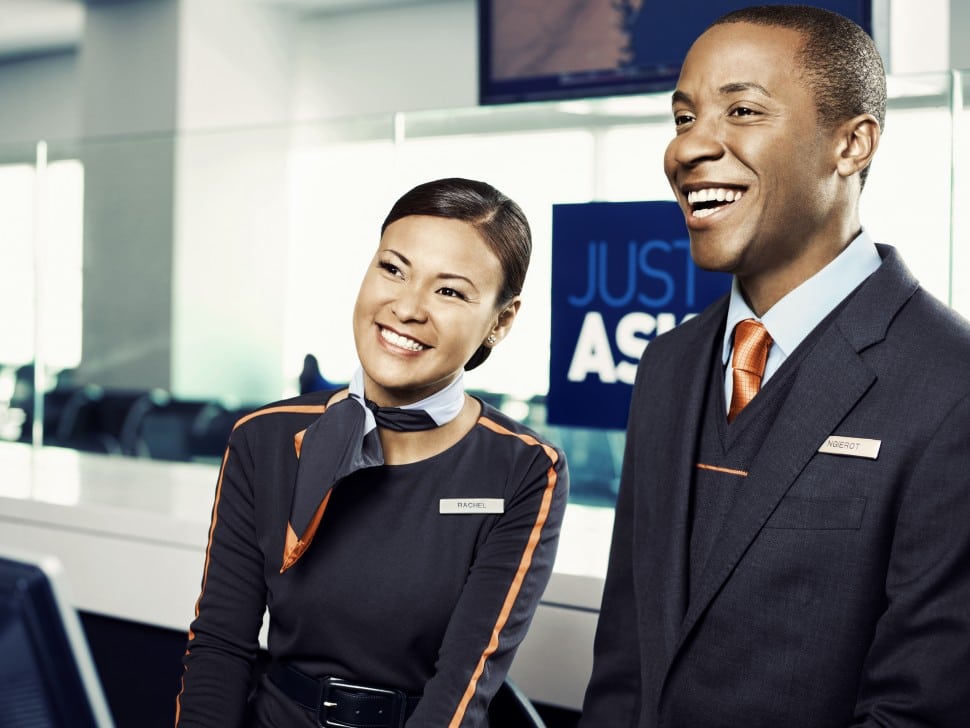 A female and male JetBlue flight attendant smiling at the airport