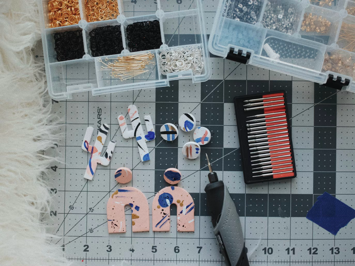 Polymer clay jewelry pieces arranged with beads and jewelry-making tools