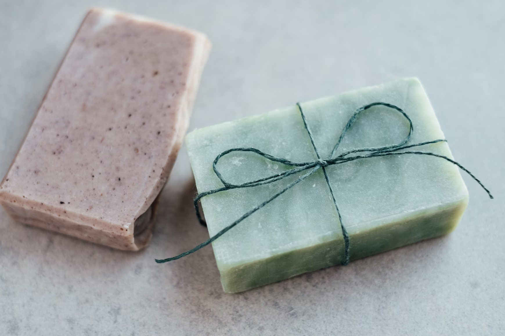 Handmade soap bars wrapped with string on a marble surface
