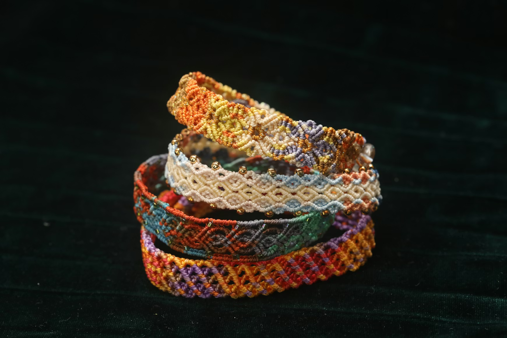 Colorful friendship bracelets stacked on a dark surface