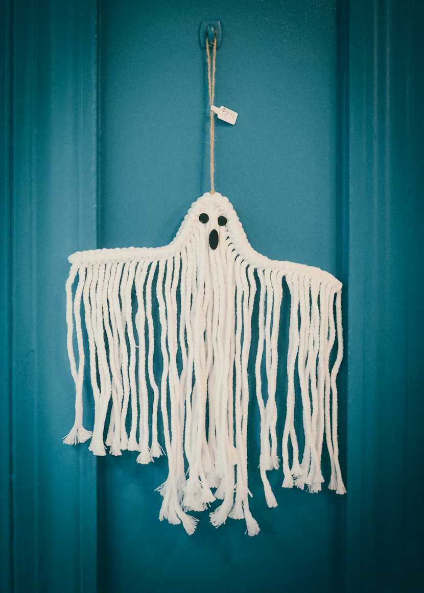 Macrame ghost decoration hanging on a teal door